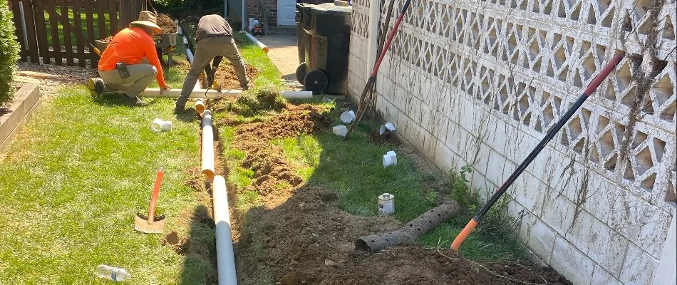 Workers digging and installing drainage pipes in yard in Louisville, KY.