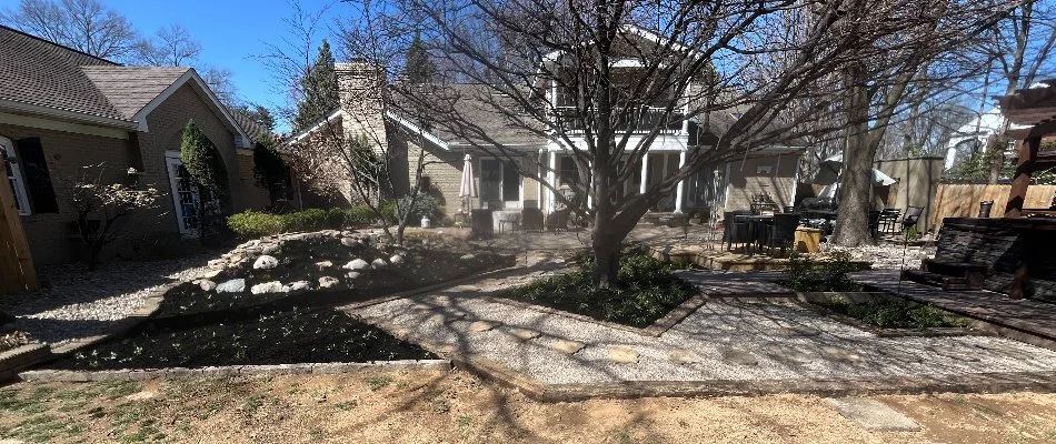 Backyard of a house in New Albany, IN, with trees, landscaping, and walkways.