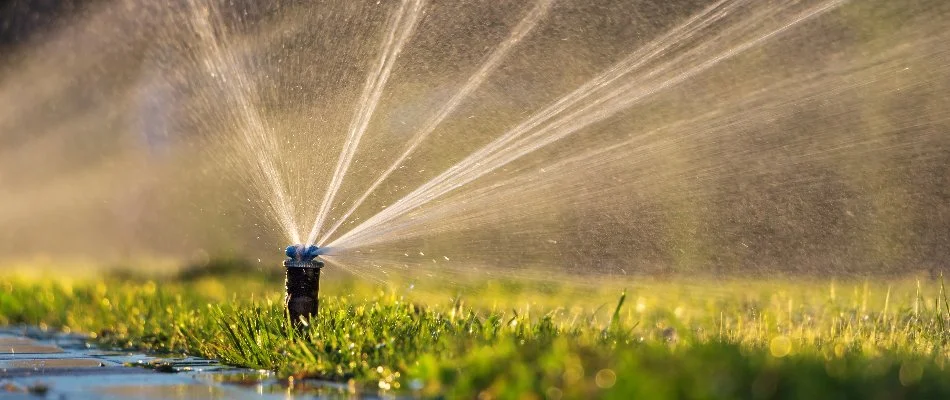 Lawn in Worthington Hills, KY, with running irrigation sprinkler head.